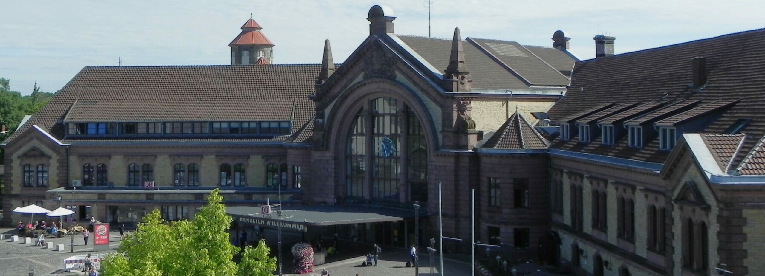 Das Empfangsgebäude des Osnabrücker Hauptbahnhofs von 1895. Im Hintergrund ist der historische Wasserturm zu sehen. Das Bild wurde am 17.07.2022 vom Oberdeck des Parkhauses von M. Beermann aufgenommen.